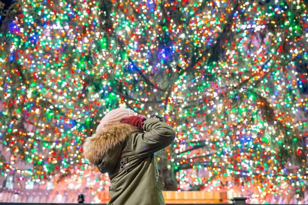 child looking up at Rockefeller Christmas tree in New York City
