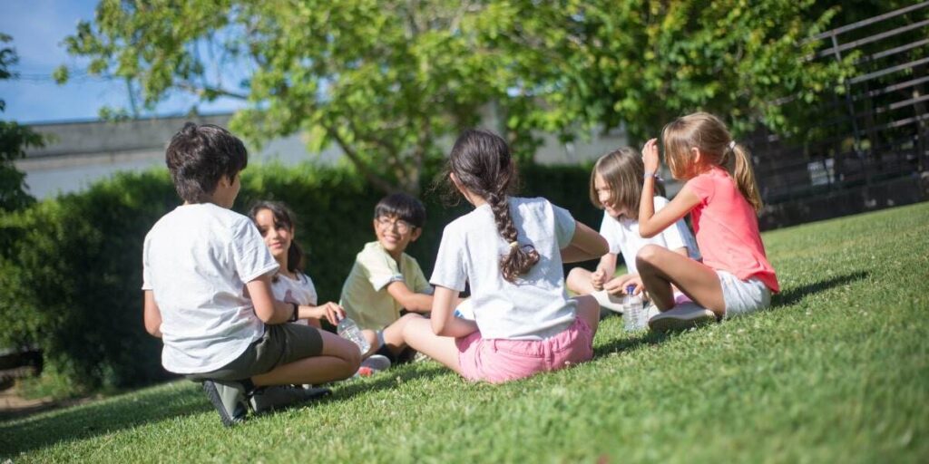 children sitting in circle on grass practicing mindfulness game