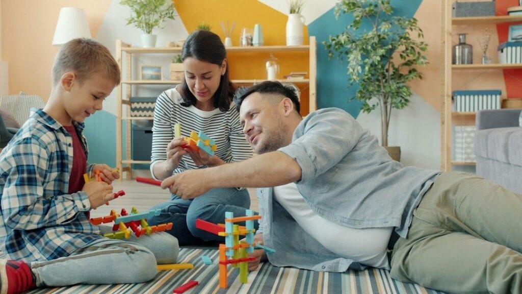 Family building with colorful toy blocks together on floor